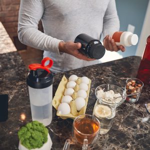 Cropped photo of a Caucasian male holding a pair of dietary supplements in his hands