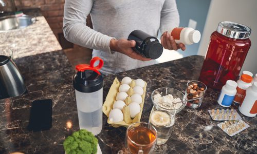 Cropped photo of a Caucasian male holding a pair of dietary supplements in his hands